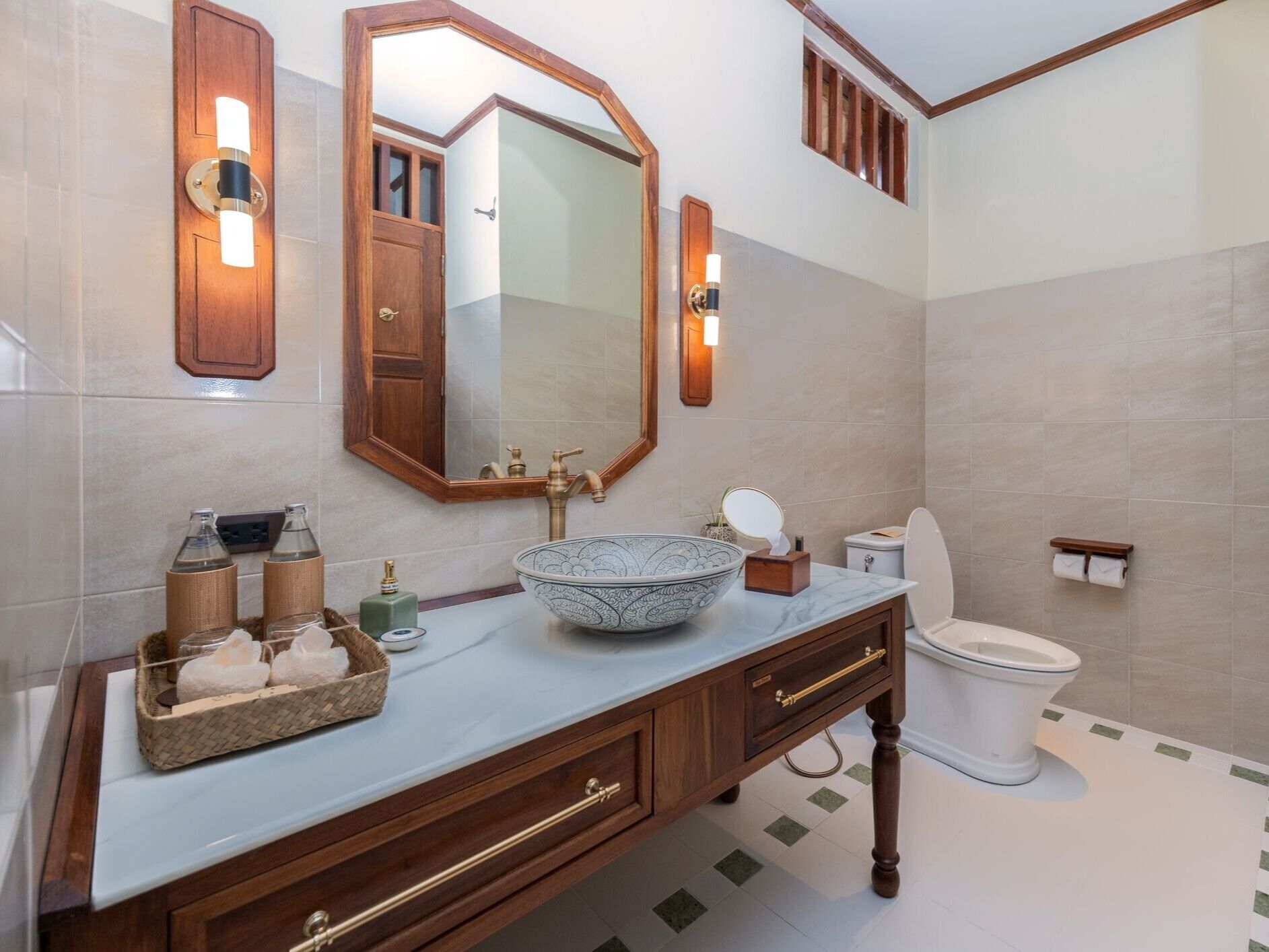 Un baño con un espejo grande, un tocador de madera, un lavabo y un inodoro.