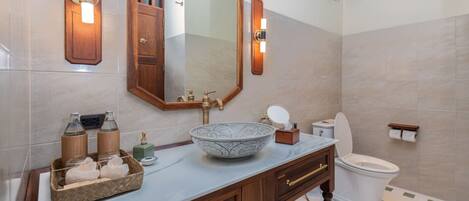 Un baño con un espejo grande, un tocador de madera, un lavabo y un inodoro.