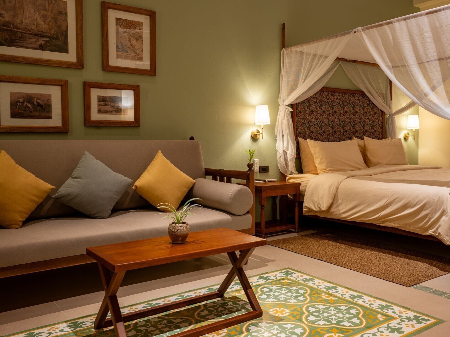 Une chambre d’hôtel avec un lit, un canapé, une petite table et un tapis décoratif.