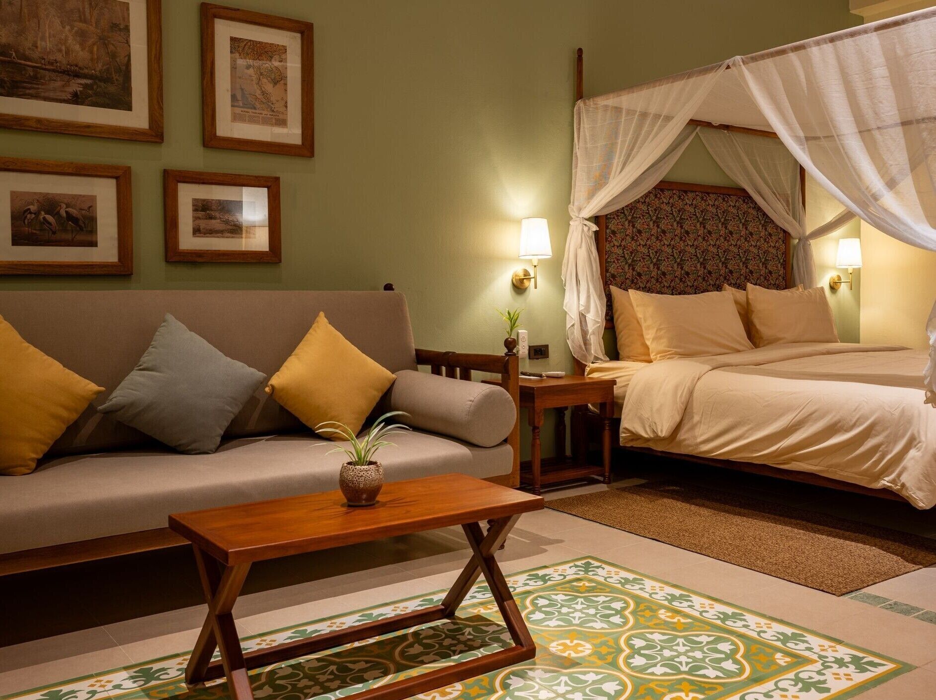 A hotel room with a bed, a sofa, a small table, and a nightstand.