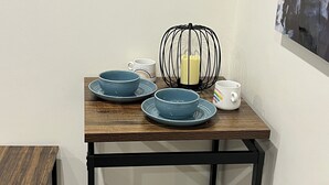 A small dining area with a wooden table and benches, featuring blue plates and a candle holder.