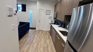 A modern kitchen with wooden flooring, stainless steel appliances, and a blue accent wall.