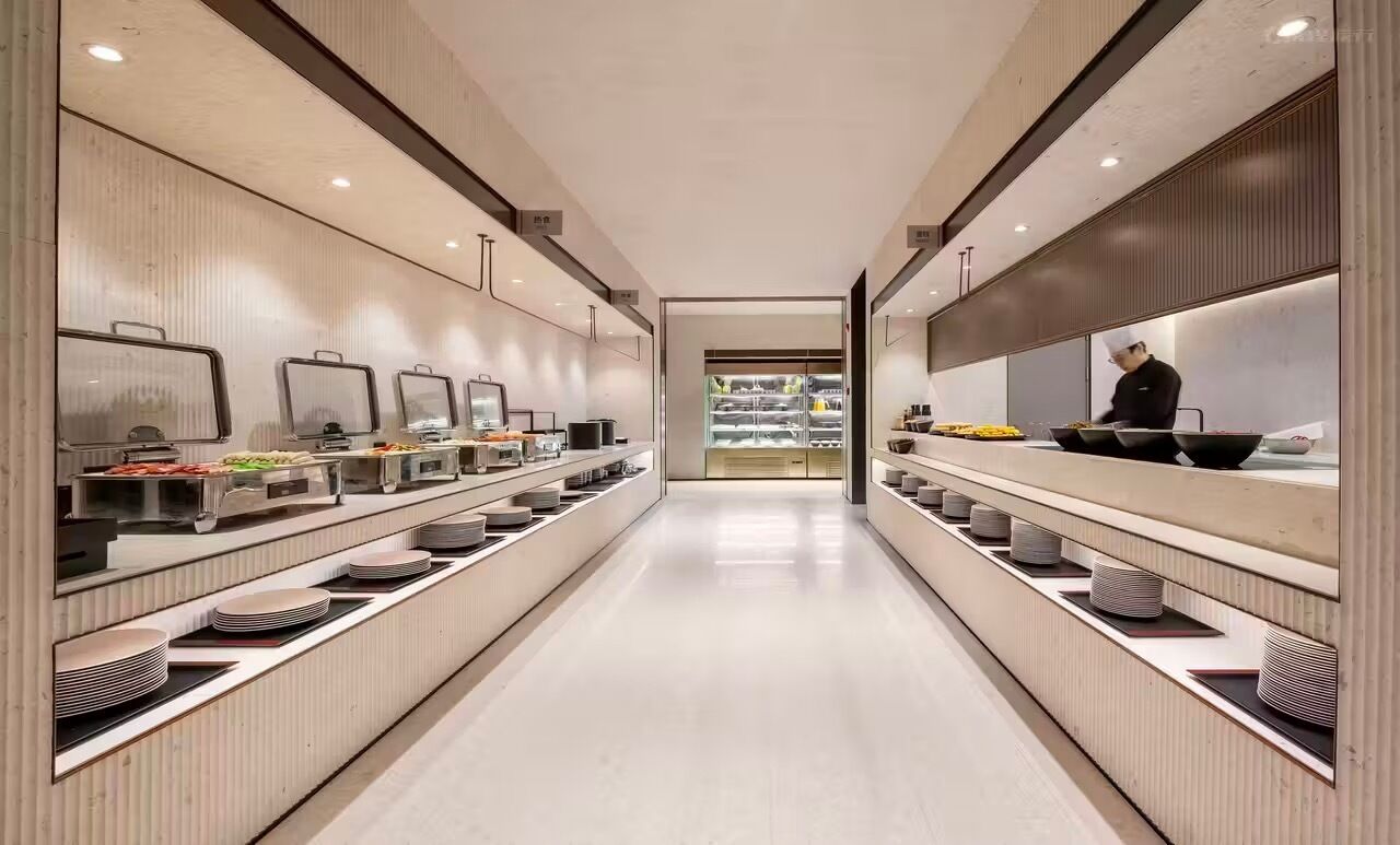 A modern kitchen with stainless steel appliances, a chef preparing food, and neatly arranged food items on shelves.