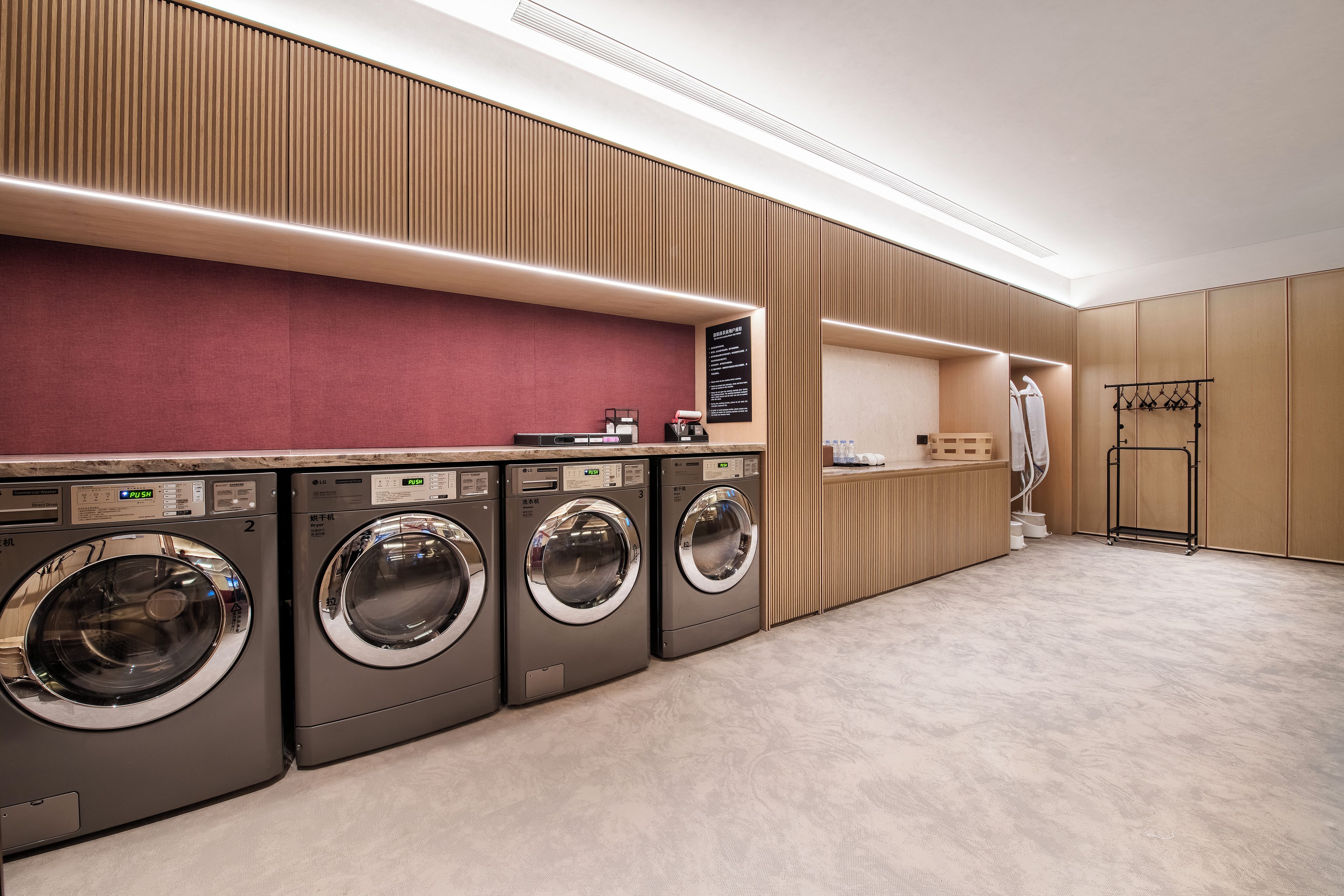 A laundry facility with four washing machines, a drying machine, and a towel rack.