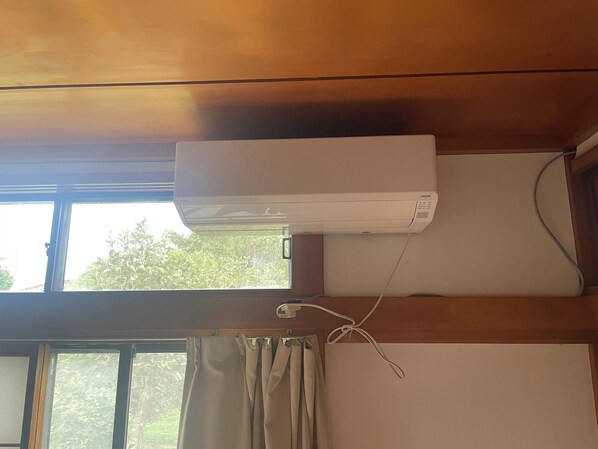 A room with a window, a curtain, and an air conditioning unit mounted on the wall. - Tensen Inn on the bay (Nikaho)