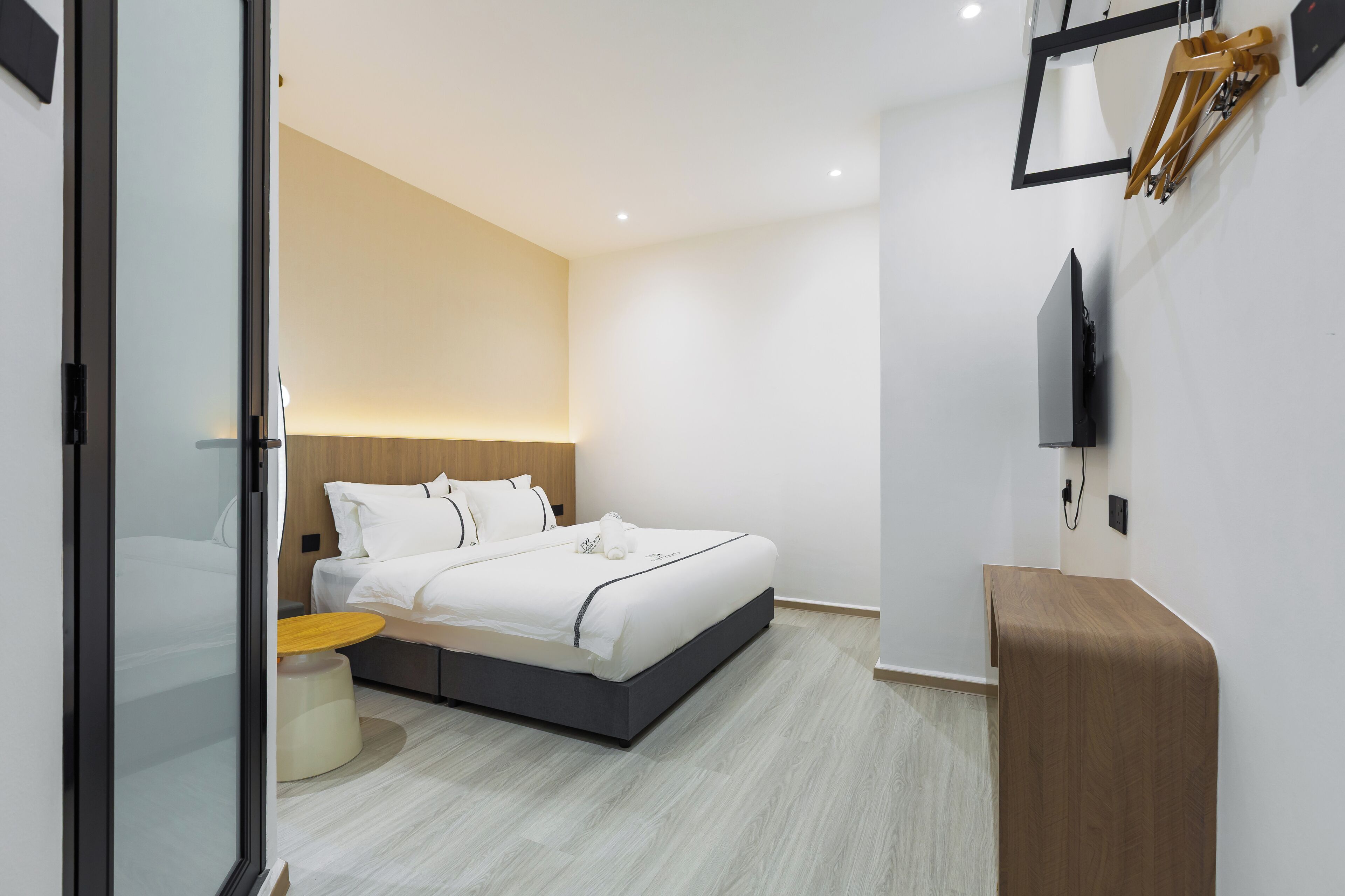 A modern bedroom with a bed, bedside table, and a TV mounted on the wall.