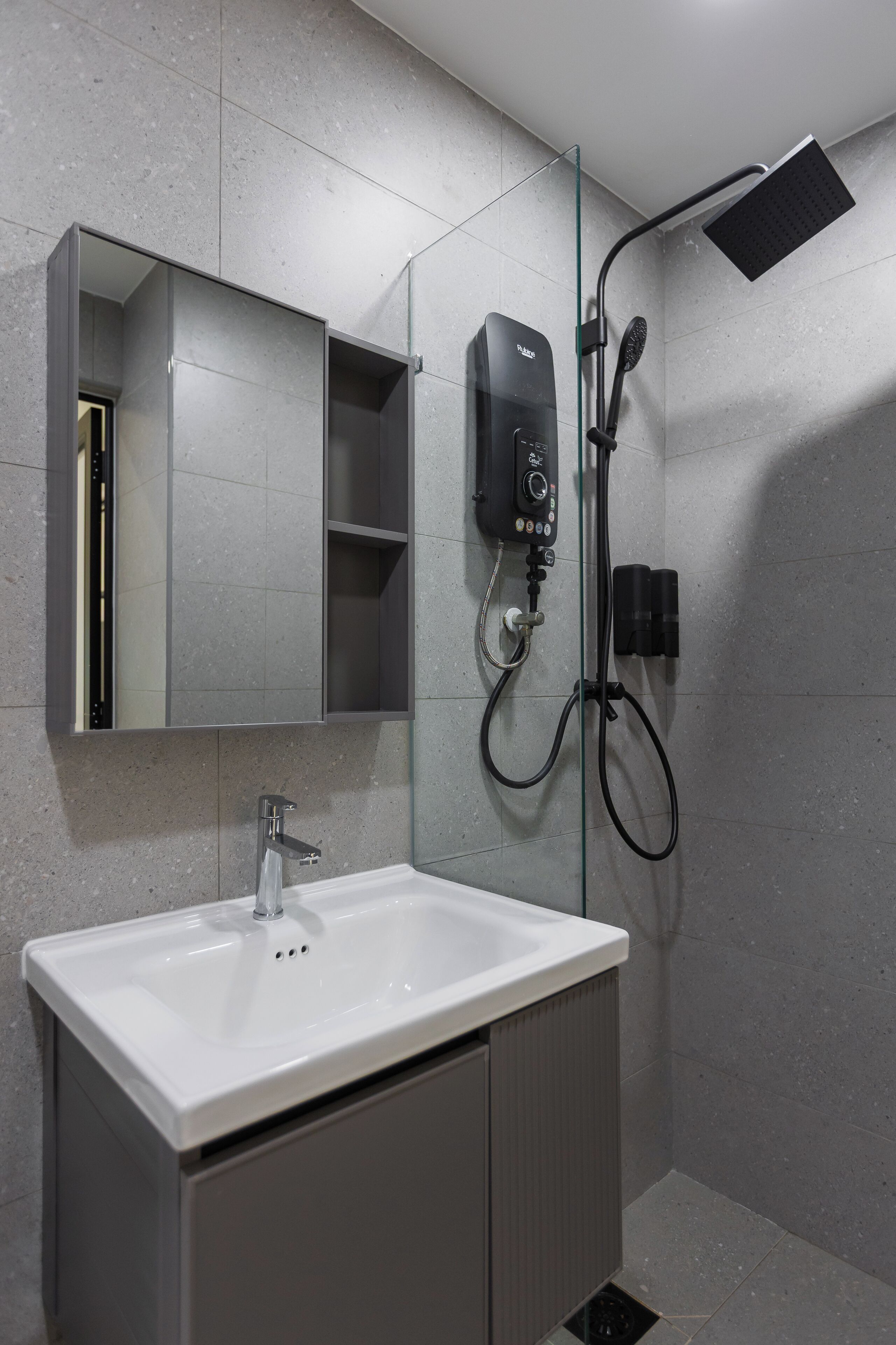 A modern bathroom with a white sink, a glass shower enclosure, and a wall-mounted control panel.