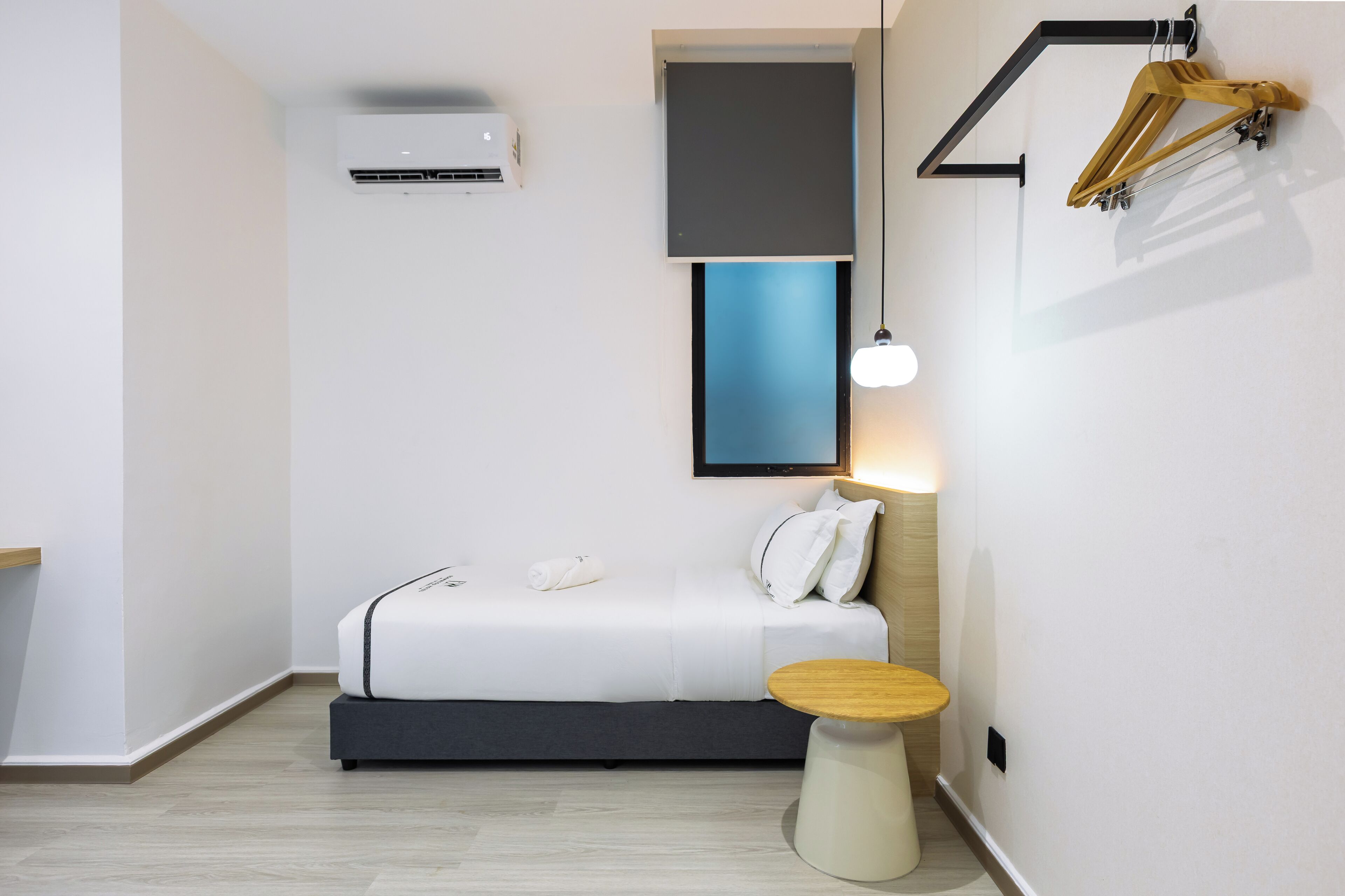 A modern bedroom with a bed, bedside table, and a wall-mounted air conditioner.