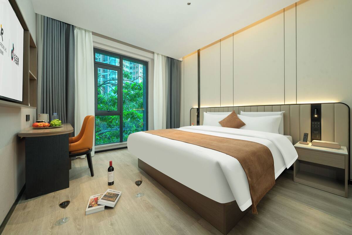 Habitación de hotel moderna con una cama grande, un escritorio y vistas a zonas verdes.