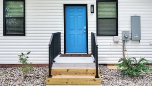 A white house with a blue door, black railings, and a small garden with rocks and plants. - The Jewel – Modern Retreat Near YMCA & Downtown (Wilmington)