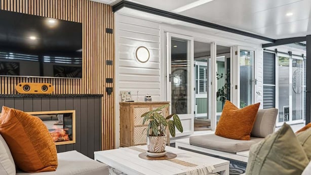 Een moderne woonkamer met een flatscreen televisie, een houten accentmuur, een open haard en een groot raam.