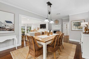 A dining area with a wooden table, wicker chairs, and a woven rug.