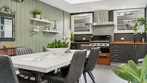 Een moderne keuken met een eethoek, met een ingebouwde oven, een afzuigkap en een raam met uitzicht.
