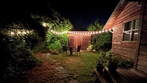 A backyard with a wooden deck, a table and chairs, and string lights.
