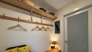 Un pasillo con un banco de madera, una cesta y un perchero de pared con ganchos.