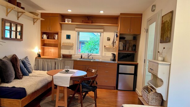 A compact kitchen with wooden cabinets, a dining table, and a built-in refrigerator.
