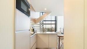 A modern kitchen with white cabinetry, a built-in oven, and a window overlooking a cityscape.