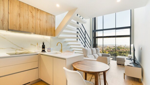 A modern kitchen with a marble countertop, a built-in oven, and a wooden cabinet.