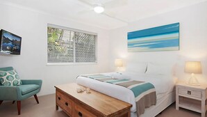 Ein Schlafzimmer mit einem Bett, einem Schreibtisch, einem Stuhl und einem Fenster mit Jalousien.