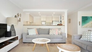Ein modernes Wohnzimmer mit einem grauen Sofa, einem Couchtisch und einem Fernseher.