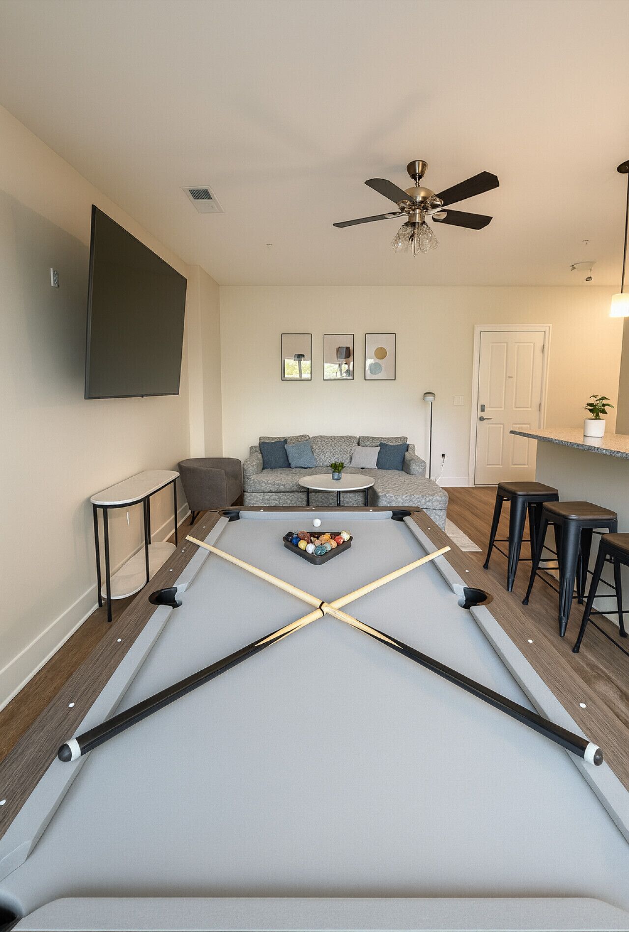 A pool table in a living room with a sofa and a ceiling fan.