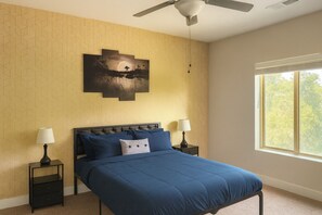 A bedroom with a bed, two nightstands, a ceiling fan, a window, and a wall-mounted artwork. - Spacious 2BR/2BA Condo Across from UAB - 1Bed (Birmingham)