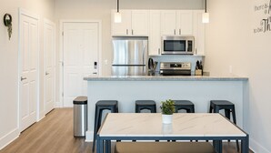 Een moderne keuken met witte kasten, roestvrijstalen apparatuur en een centraal eiland met barkrukken.