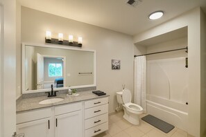 A modern bathroom with a large mirror, a sink, a toilet, and a shower area. - 🏙 Luxury 2BR Condo | Steps from UAB Campus 5a (Birmingham)