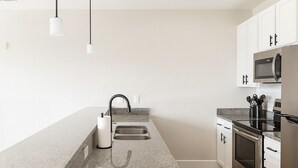 A modern kitchen with granite countertops, stainless steel appliances, and white cabinetry.