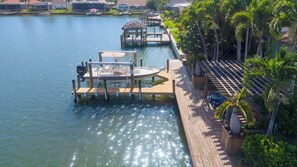 A marina with boats docked, a wooden dock, and a palm tree-lined walkway.