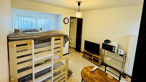 A compact room with a bunk bed, a small TV, a coffee machine, and a table with a remote control. - GUEST HOUSE TEN (Osaka)