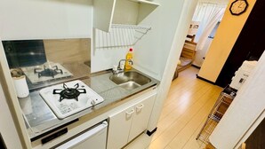 A compact kitchen with a gas stove, a sink, and a small countertop. - GUEST HOUSE TEN (Osaka)