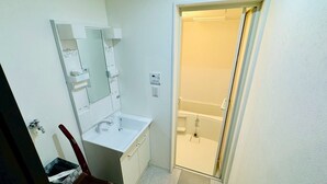 A small, compact bathroom with a white sink, mirror, and shower. - GUEST HOUSE TEN (Osaka)
