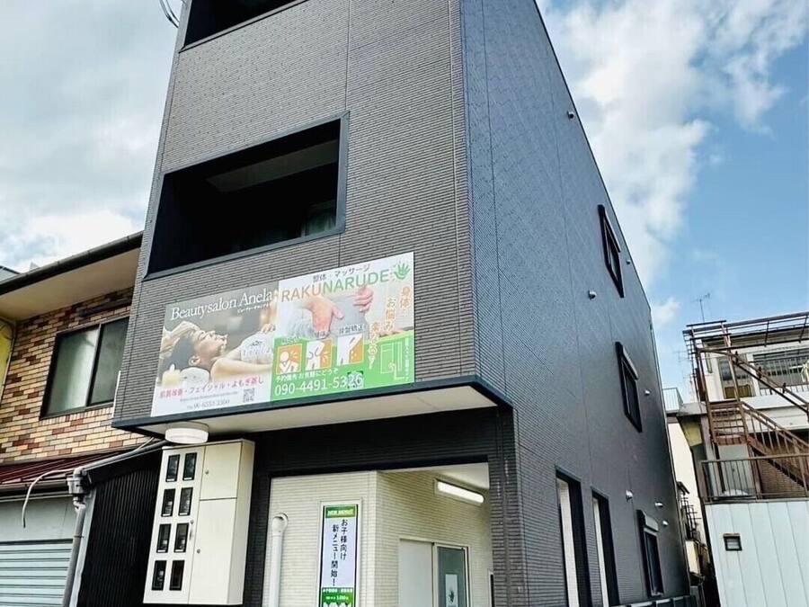 Un bâtiment moderne à la façade grise, avec une devanture visible et une enseigne indiquant un salon de beauté.