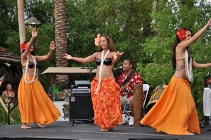 A stage with performers in traditional attire, a sound system, and a tropical backdrop.