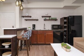 A modern kitchen with wooden cabinets, a black refrigerator, a microwave, and a coffee maker.