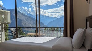 A hotel room with a large window offering a mountain view. - HARD ROCK HUNZA (Karimabad)