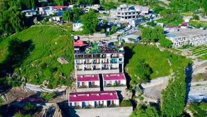 An aerial view of a resort with multiple buildings, a swimming pool, and lush greenery. - HARD ROCK HUNZA (Karimabad)