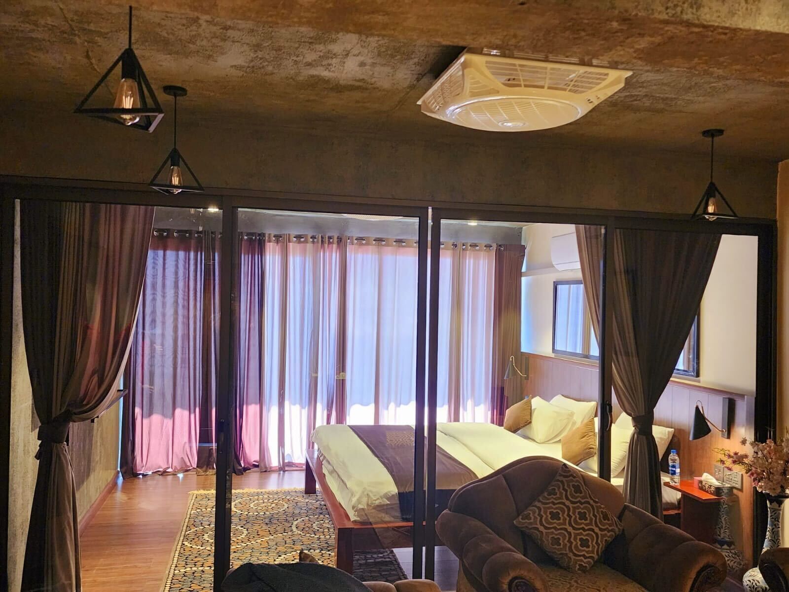 A spacious room with a large bed, a sofa, and a dining area.