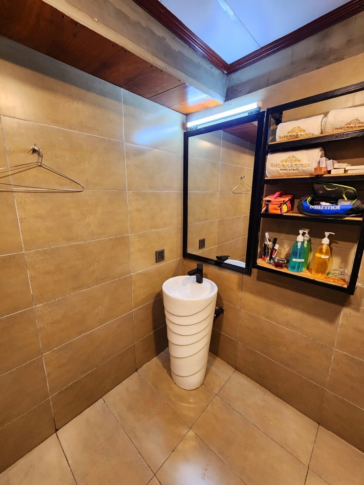 Un baño con un lavamanos blanco, un espejo y un estante con artículos de tocador.