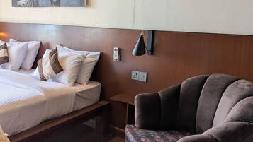 Una habitación de hotel con una cama, un sofá, un cuadro y una mesa con una caja de pañuelos.
