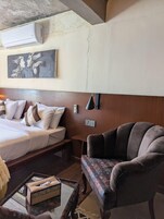 Una habitación de hotel con una cama, un sofá, un cuadro y una mesa con una caja de pañuelos.