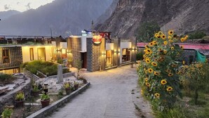 A hotel entrance with a paved pathway, potted plants, and a mountain backdrop. - HARD ROCK HUNZA (Karimabad)