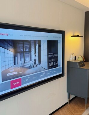 Una pantalla de televisión muestra el interior de un hotel con diseño moderno, una recepción y una lámpara de pared.