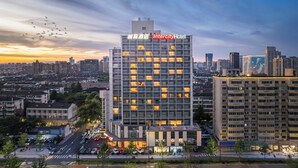 Un hotel moderno de gran altura con varios pisos, un letrero llamativo y una vista panorámica del paisaje urbano al fondo.