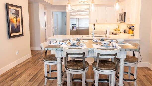 A modern kitchen with white cabinetry, a central island, and bar stools.