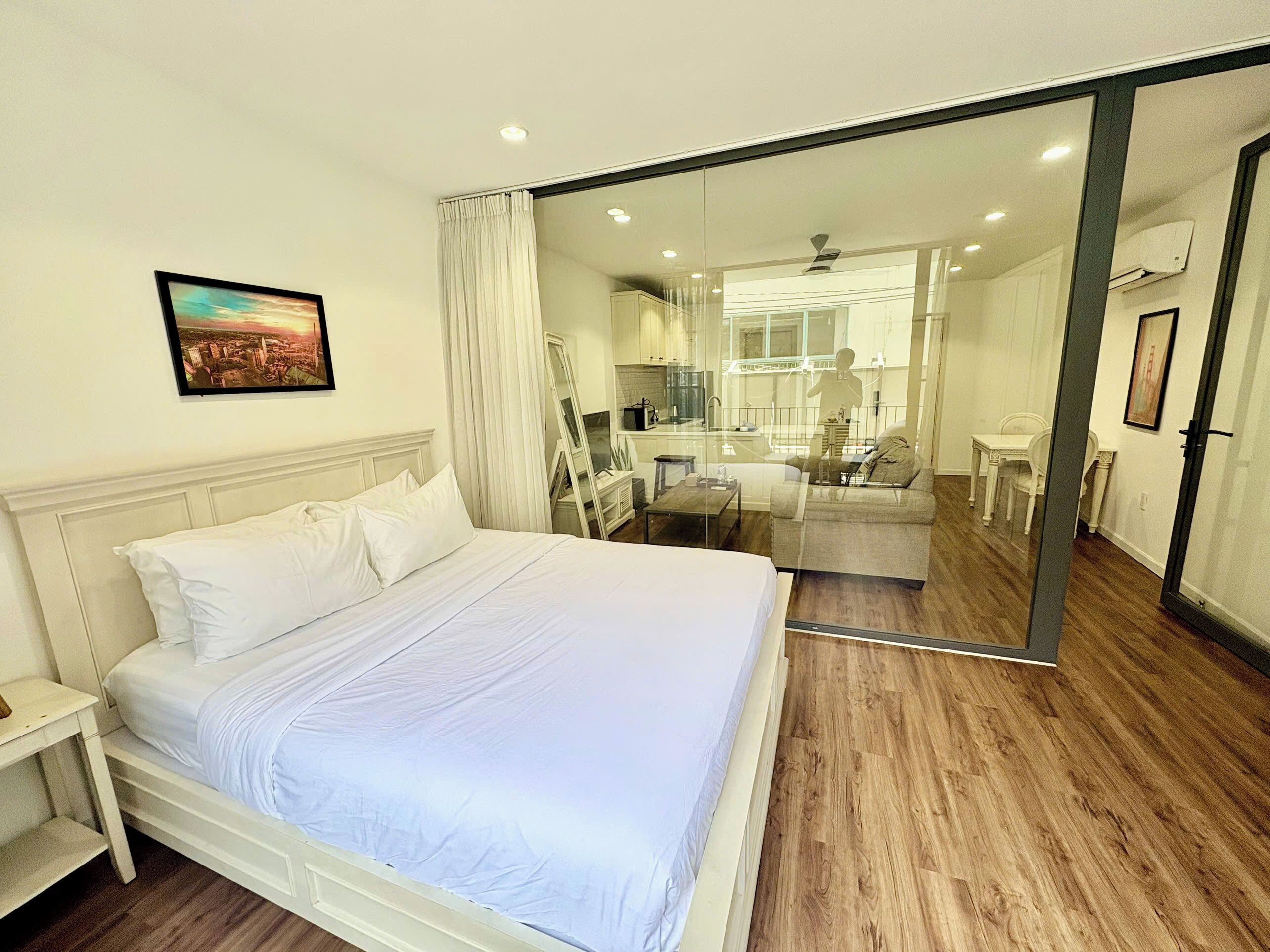 Un dormitorio con cama, mesita de noche, espejo y vista al baño.