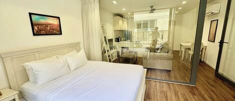 A bedroom with a bed, a nightstand, a mirror, and a view into the bathroom.