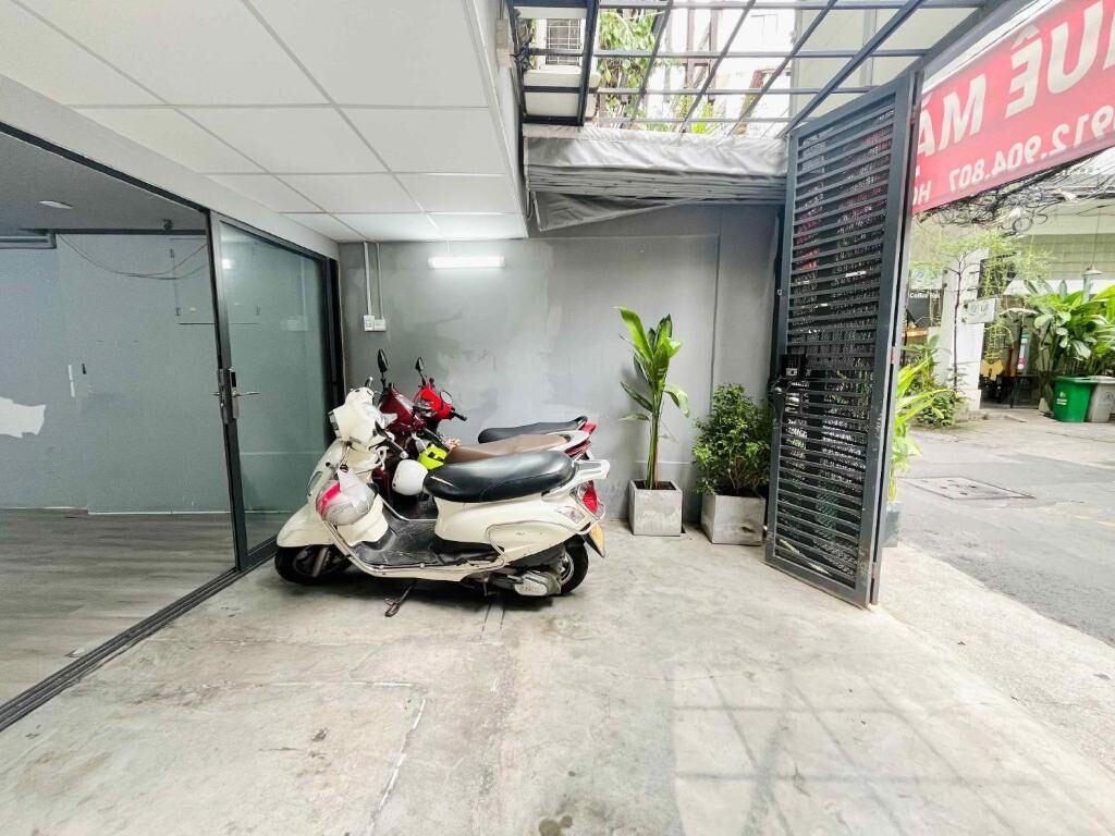 A parking area with a white scooter, a potted plant, and a metal gate.