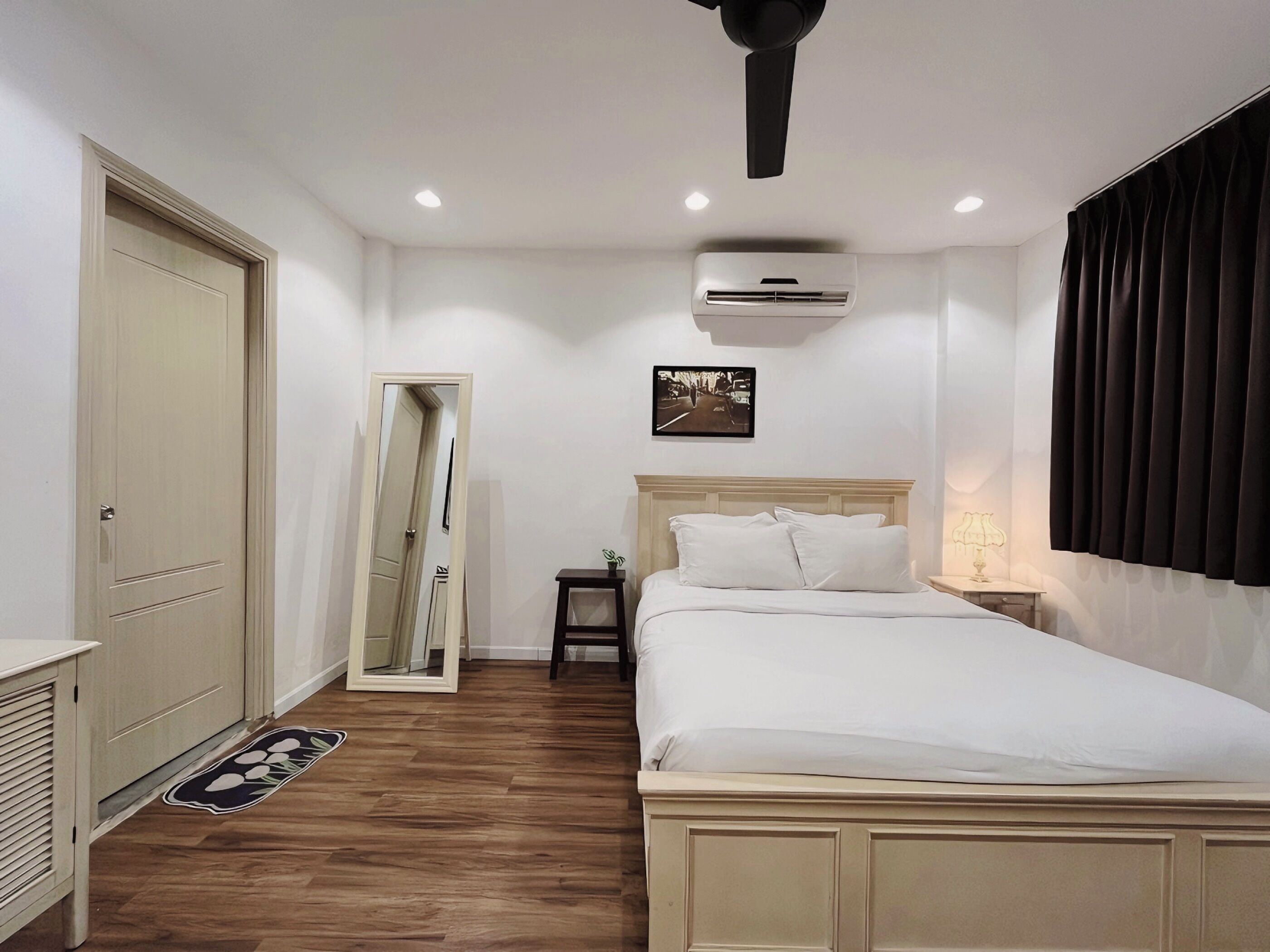 Une chambre à coucher comprenant un lit, une table de chevet, une commode et un appareil de climatisation.